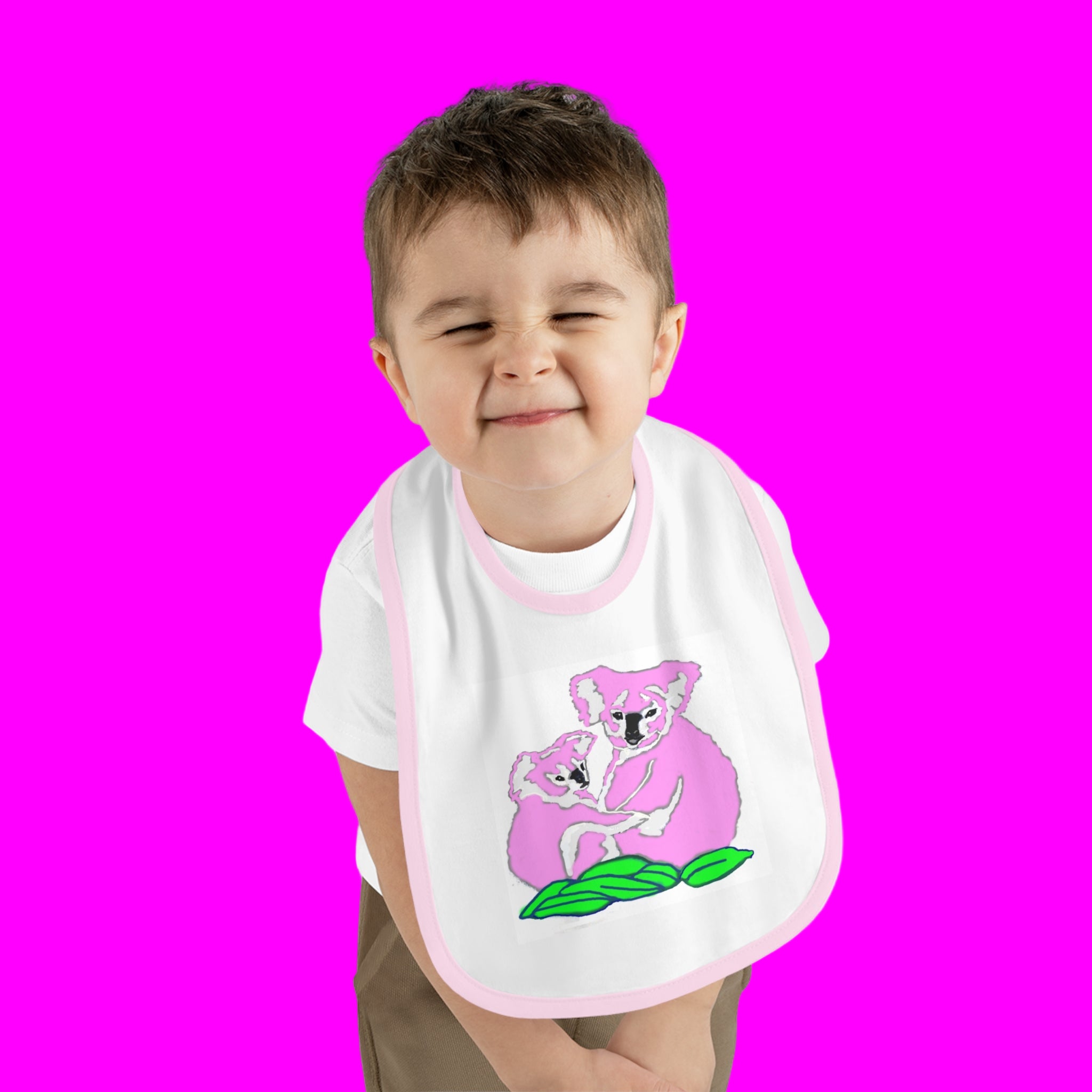 Child wearing a bib with a koala design on a pink background