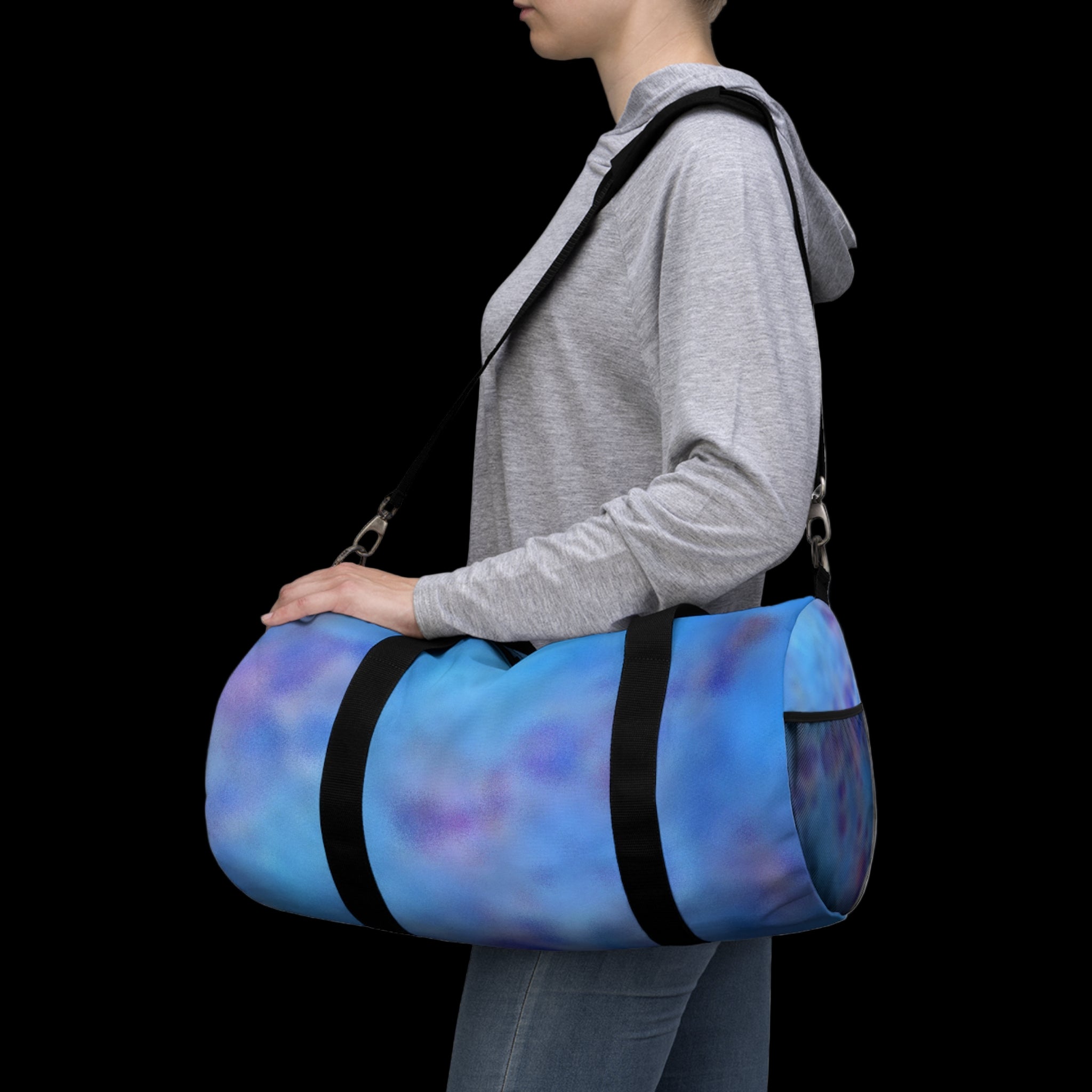 Person carrying a blue and purple duffel bag with black straps on a plain background