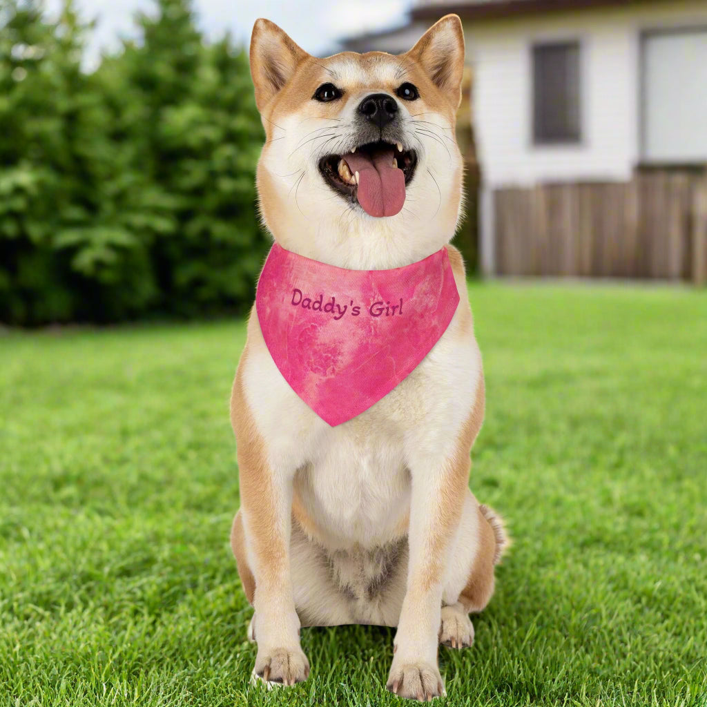 Dog wearing a pink 'Daddy's Girl' bandana on a grassy background