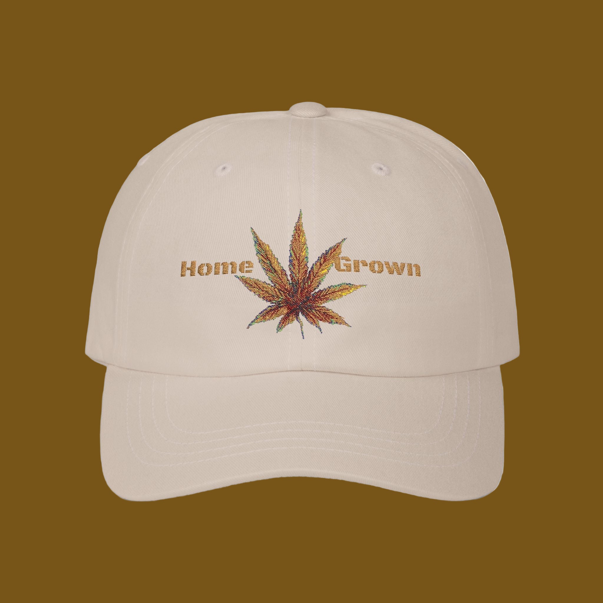 Beige cap with embroidered cannabis leaf and 'Home Grown' text on a brown background
