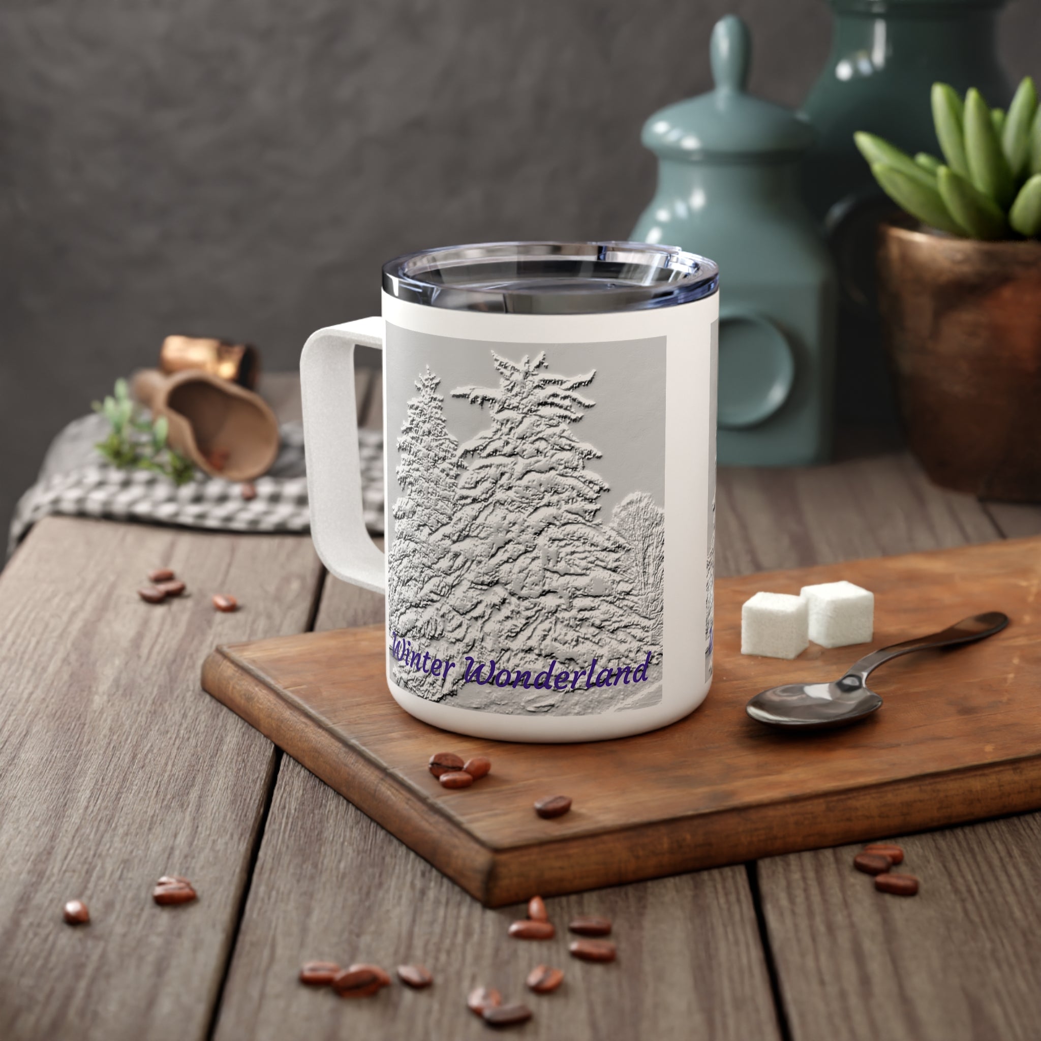 White mug with winter Wonderland design on a wooden surface with coffee beans and sugar cubes.