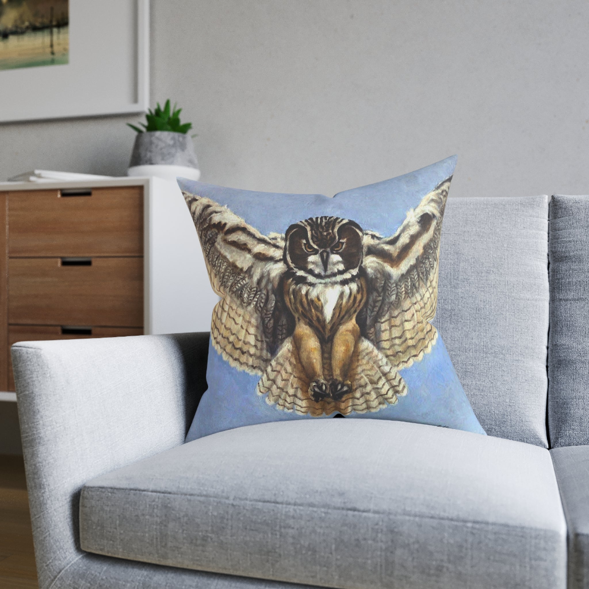 Decorative pillow with an owl design on a gray sofa in a living room setting.