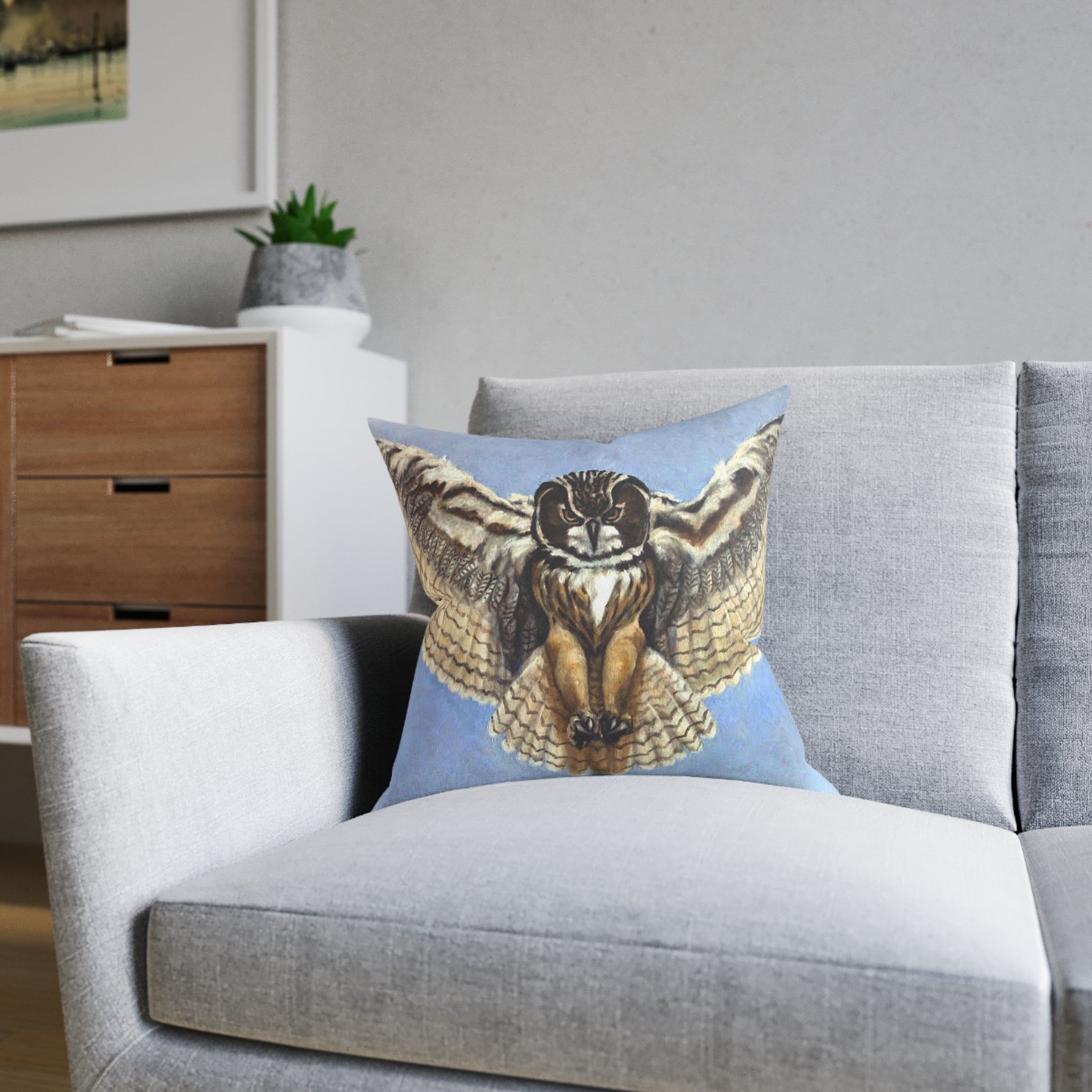 Gray sofa with a decorative pillow featuring an owl design in a living room setting.
