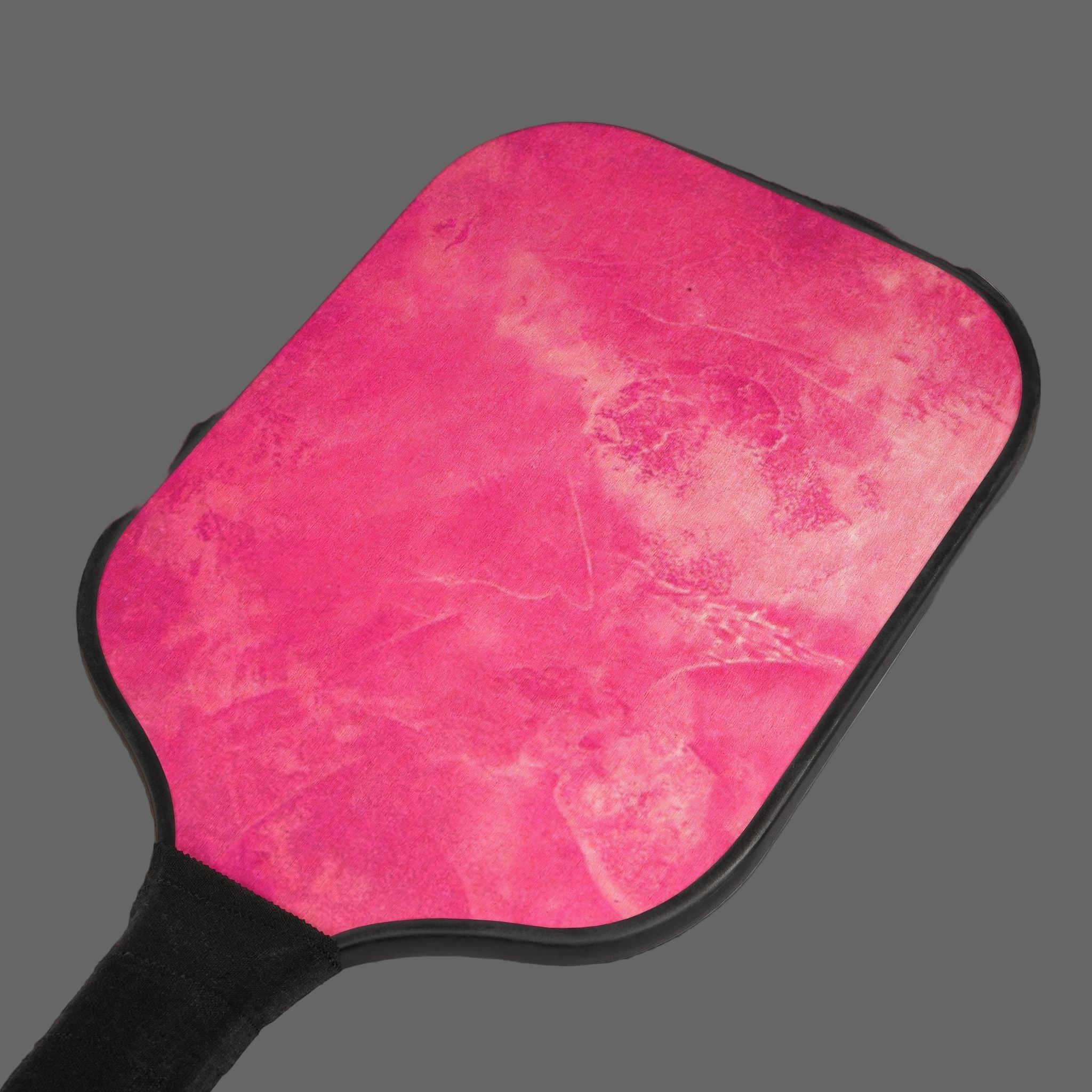 Pink textured paddle with black handle on a dark gray background