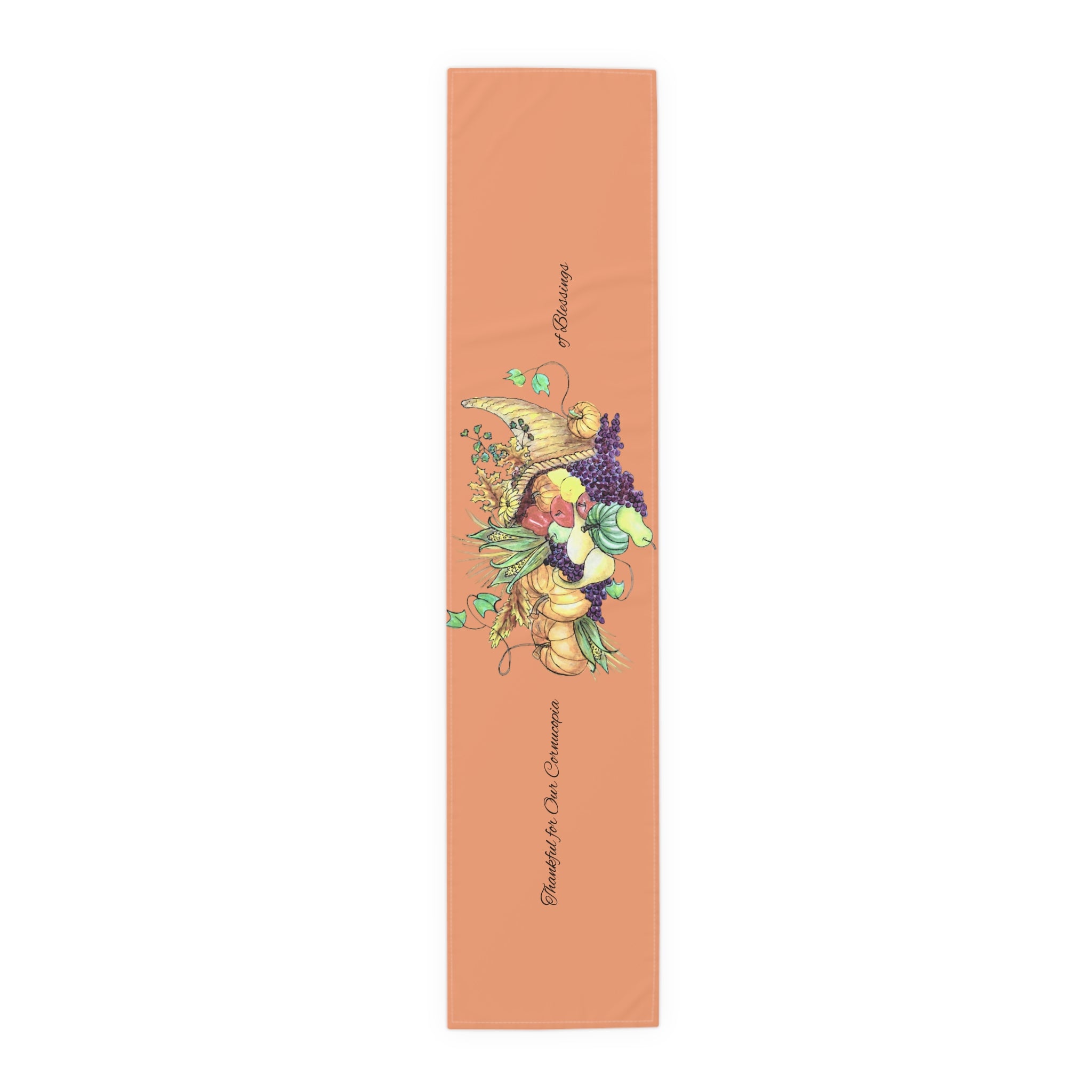 Light orange holiday table runner with a cornucopia design of fruits and vegetables on a white background