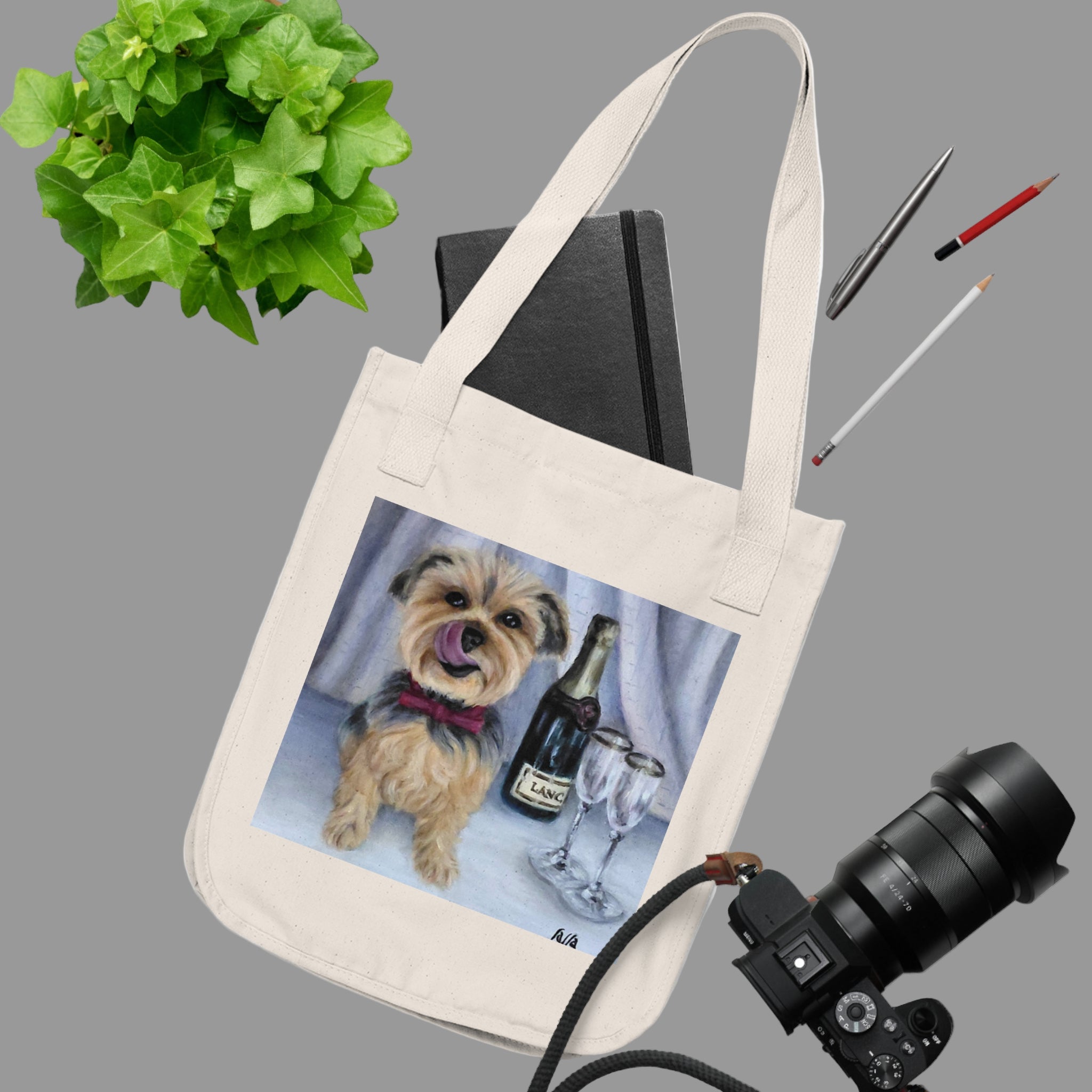 Tote bag with a dog and wine design on a white surface with stationery items.