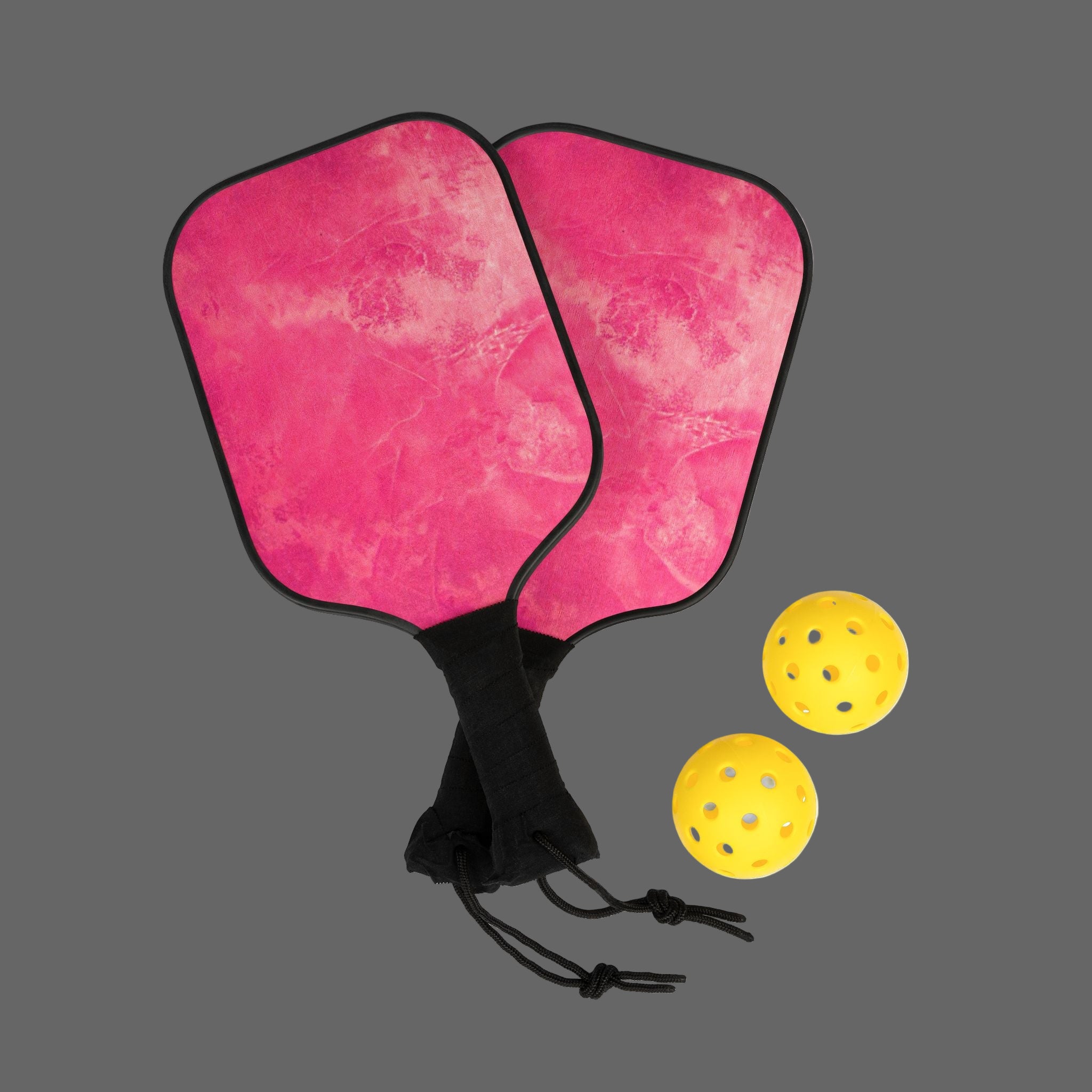 Two pink pickleball paddles with three yellow balls on a dark gray background