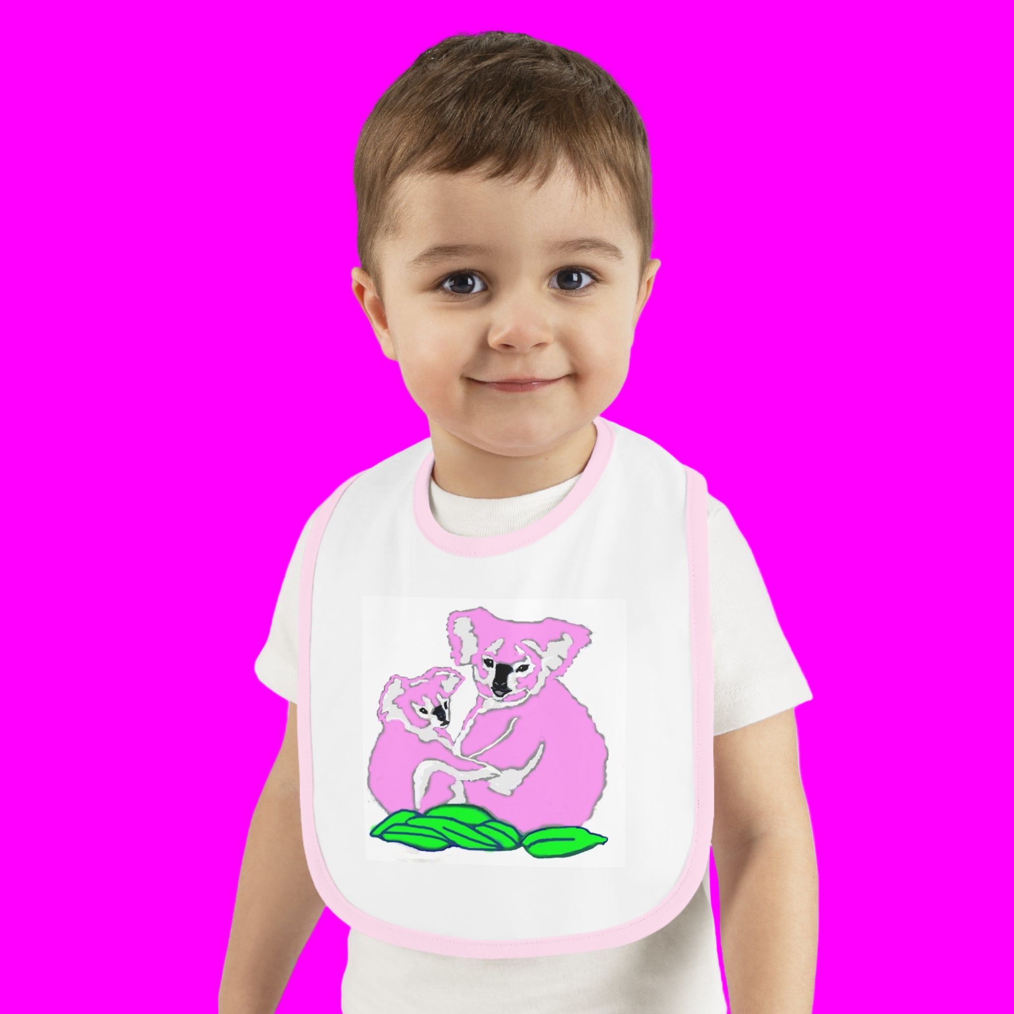 Child wearing a bib with a pink koala design on a pink background