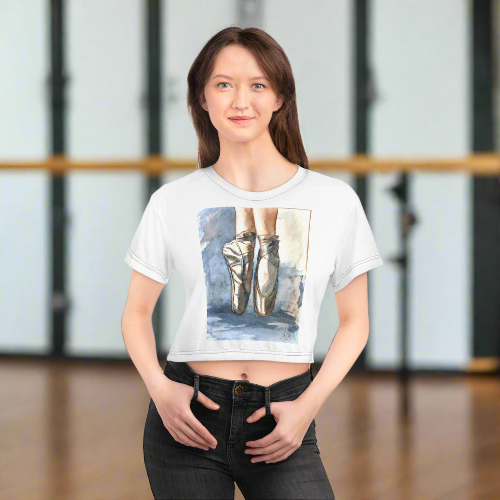 Woman wearing a white t-shirt with a graphic of ballet shoes in a ballet class background