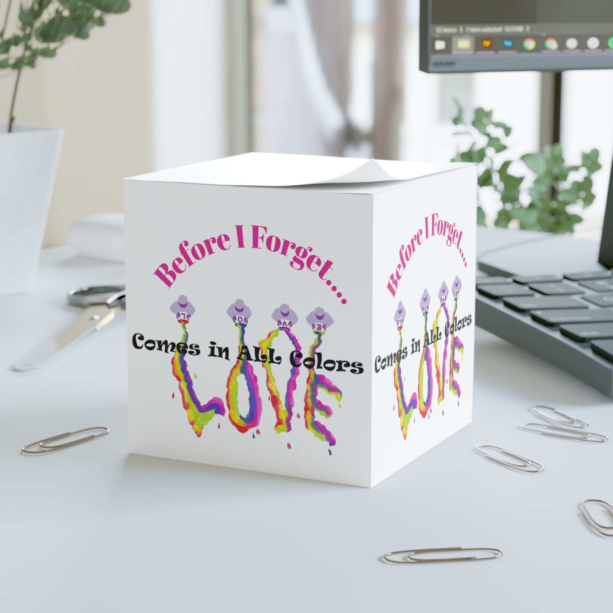 White cube with colorful 'LOVE' text on a desk with office supplies