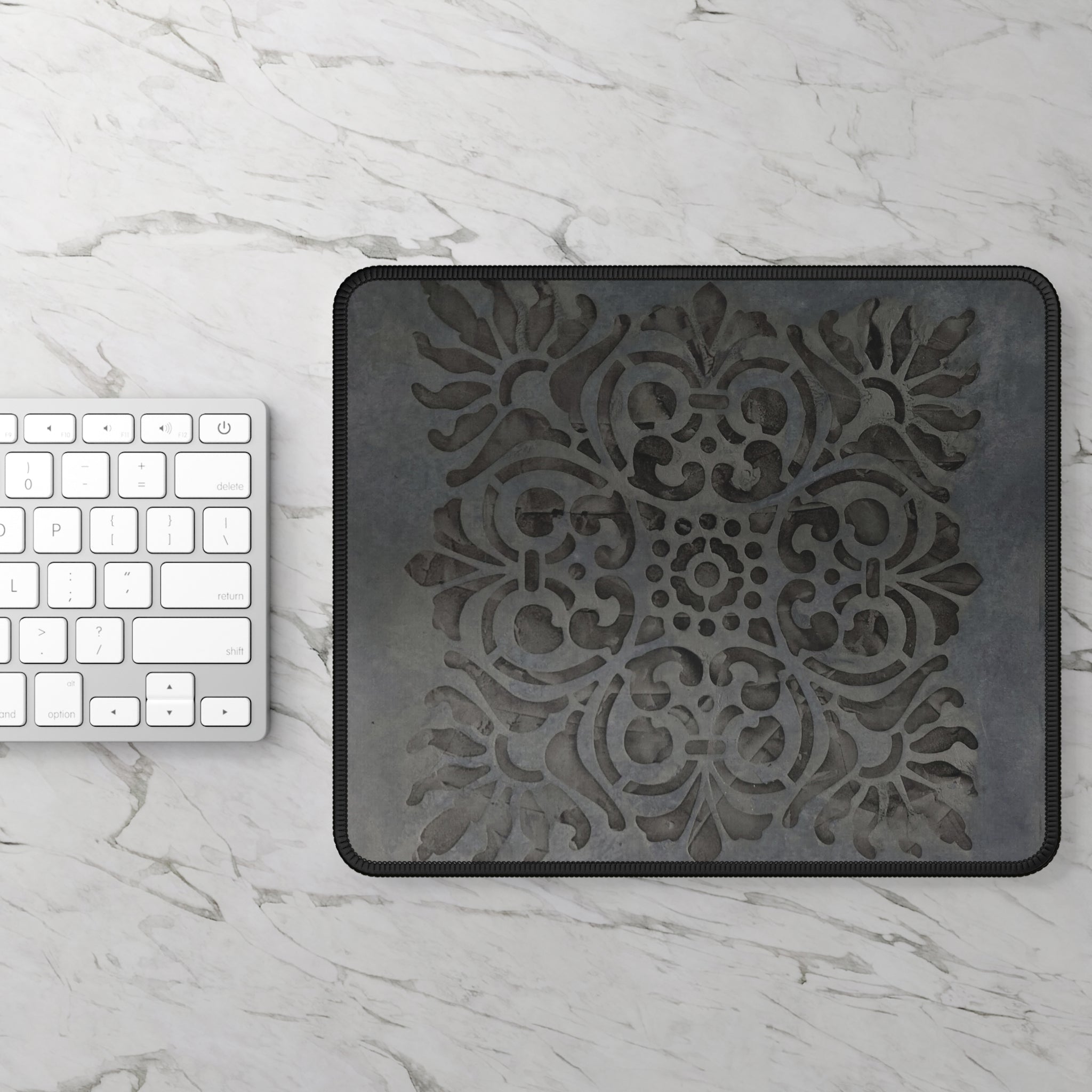 Decorative black mat with intricate design on a marble surface next to a keyboard