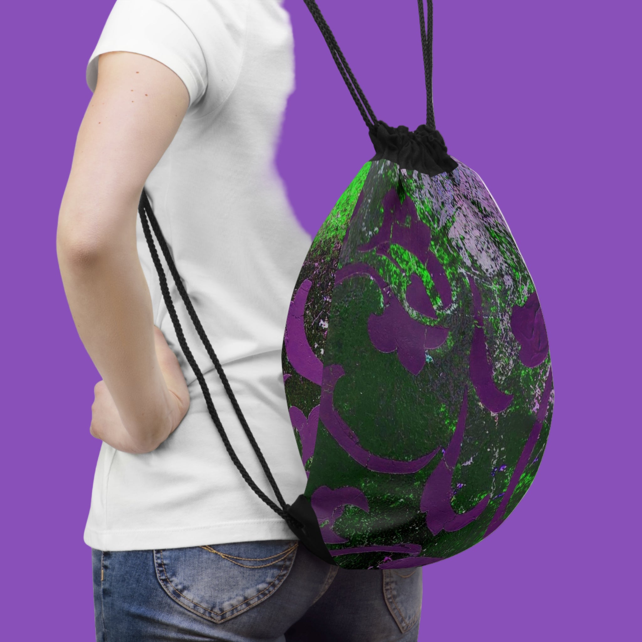 Person holding a green and purple drawstring bag on a white background