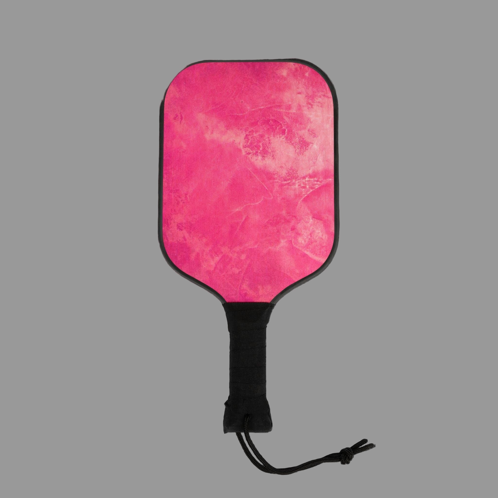 Pink pickleball paddle with black handle on a dark gray background