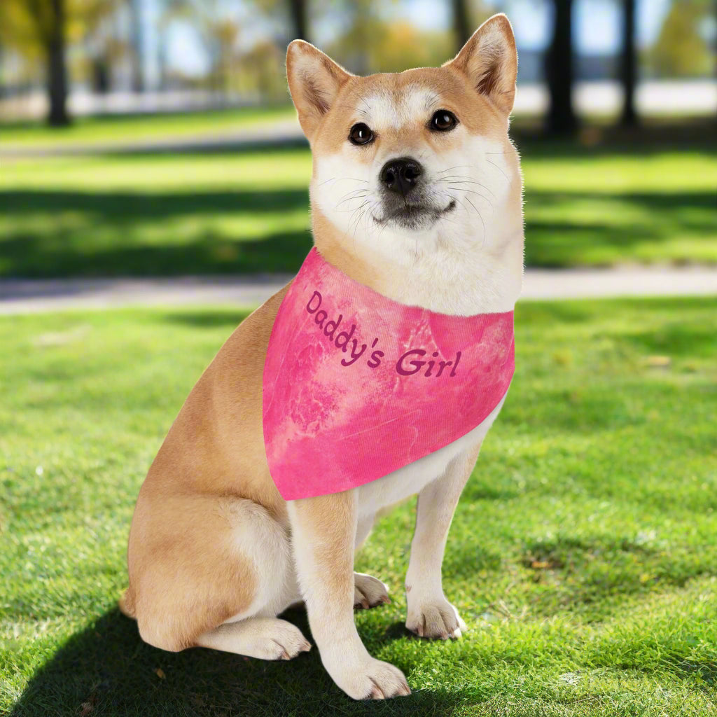 Dog wearing a pink bandana with 'Daddy's Girl' text in a grassy park