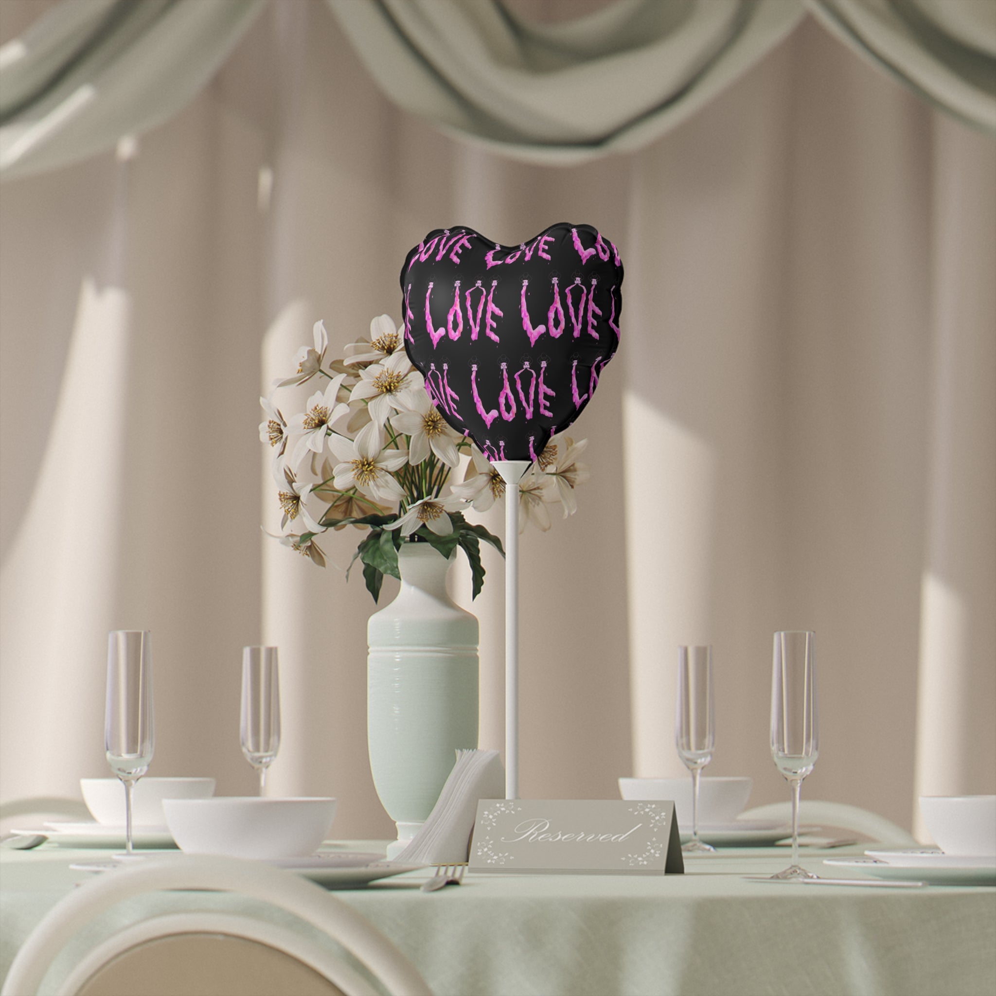 Decorative heart-shaped sign with 'LOVE' text on a table setting with flowers and glasses.