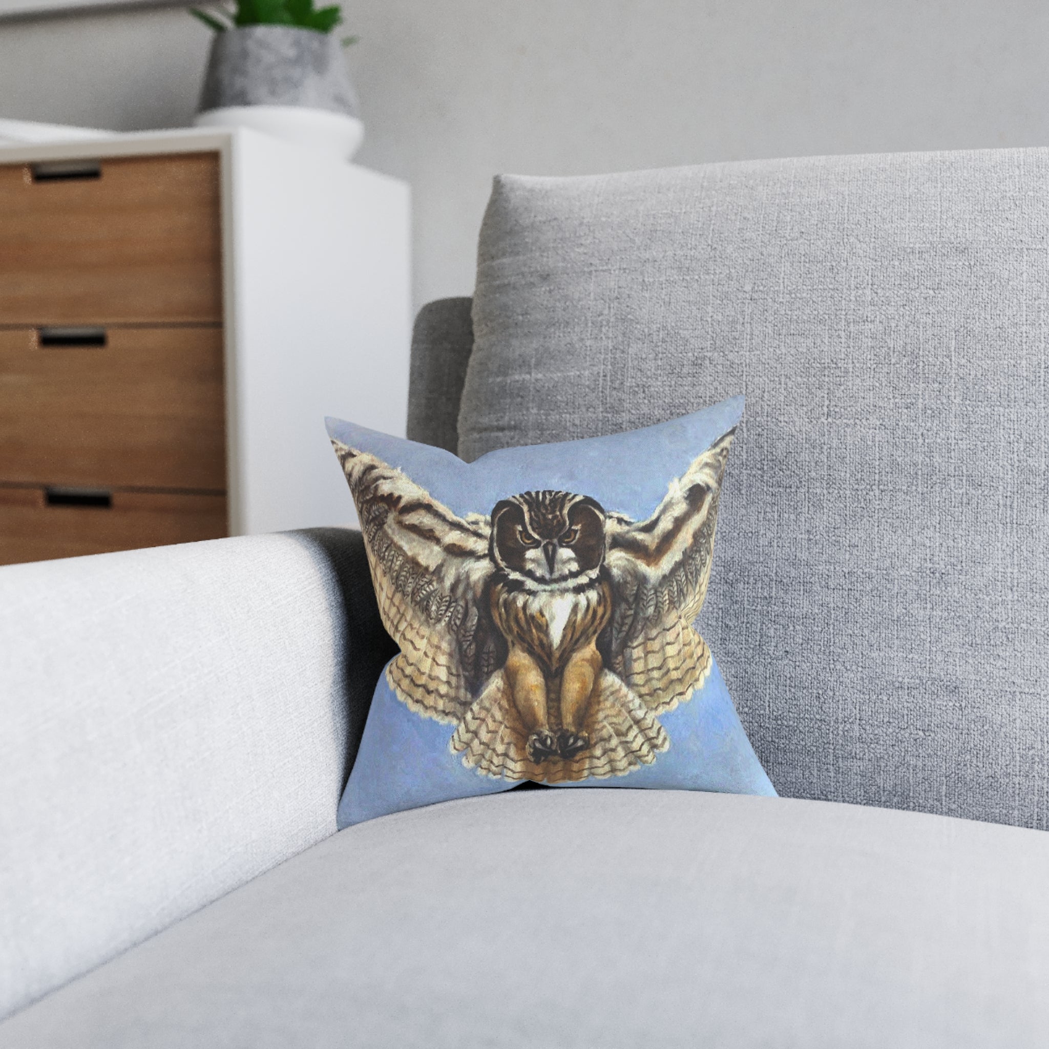Decorative pillow with an owl design on a gray sofa