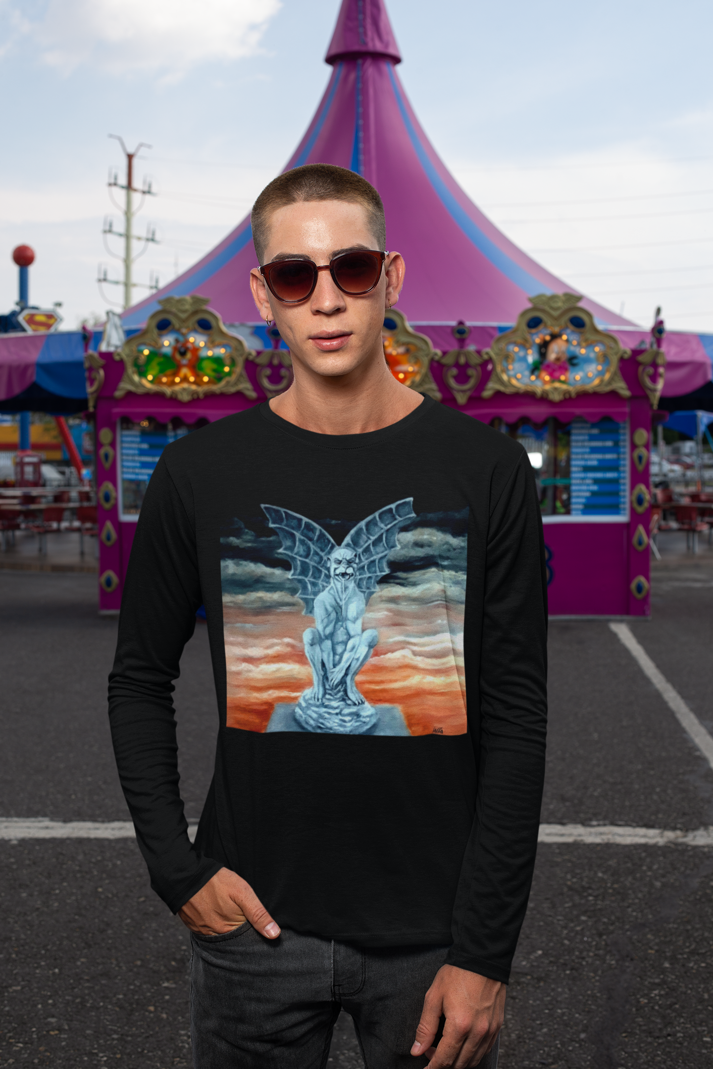 Person wearing a black long-sleeve shirt with a graphic design of a Gargoyle in front of a colorful tent at a fair.
