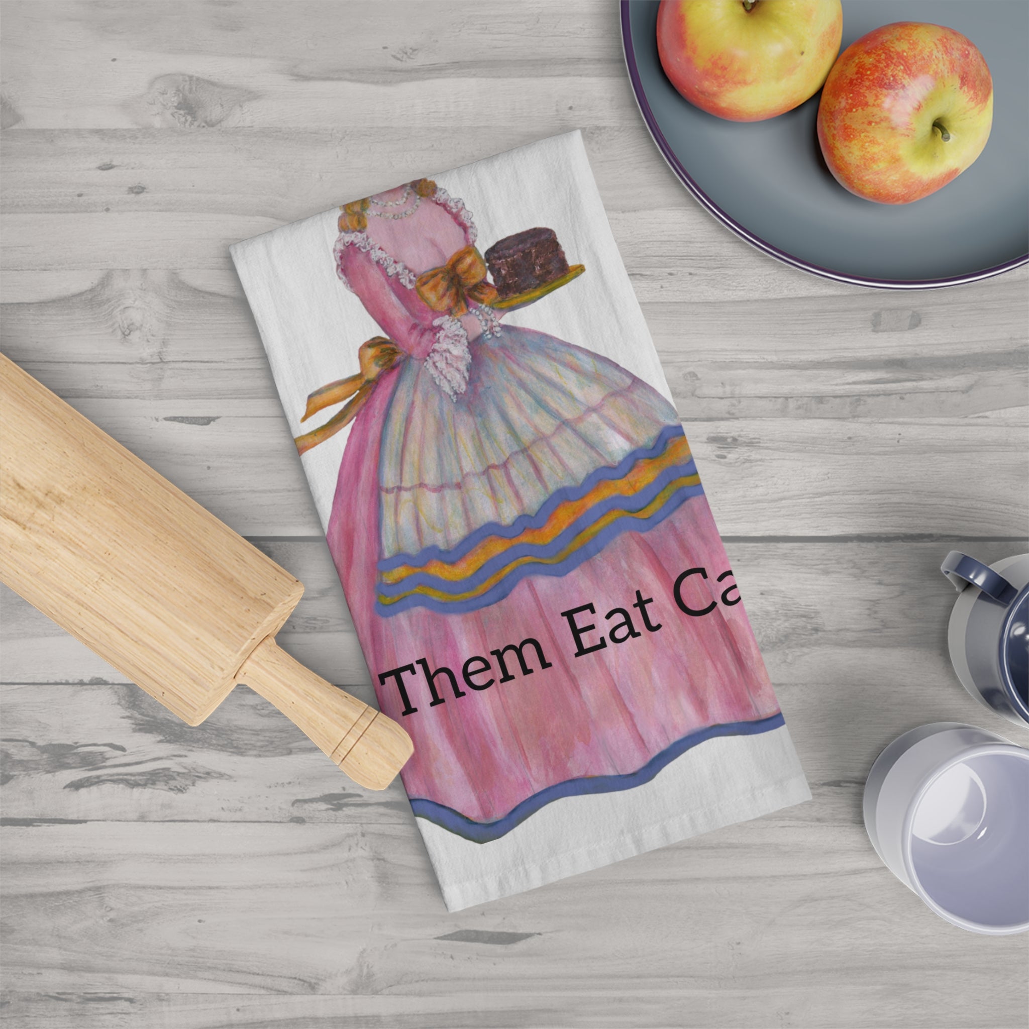 Kitchen towel with vintage illustration and text on a wooden surface with apples and a rolling pin.