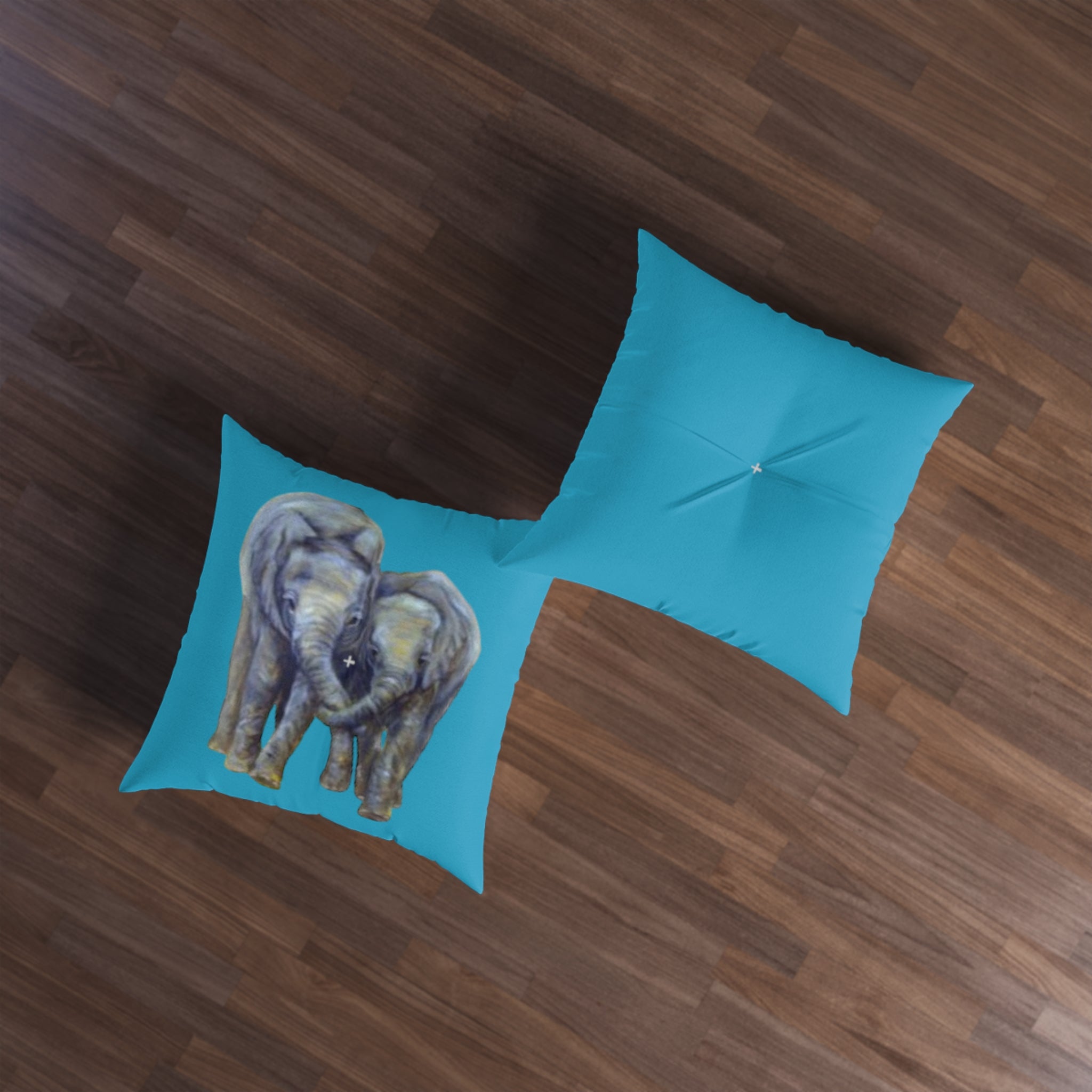 Two teal pillows with elephant designs on a wooden floor